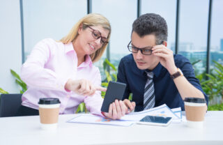 two mid adult business colleagues using phone outdoor cafe jpg